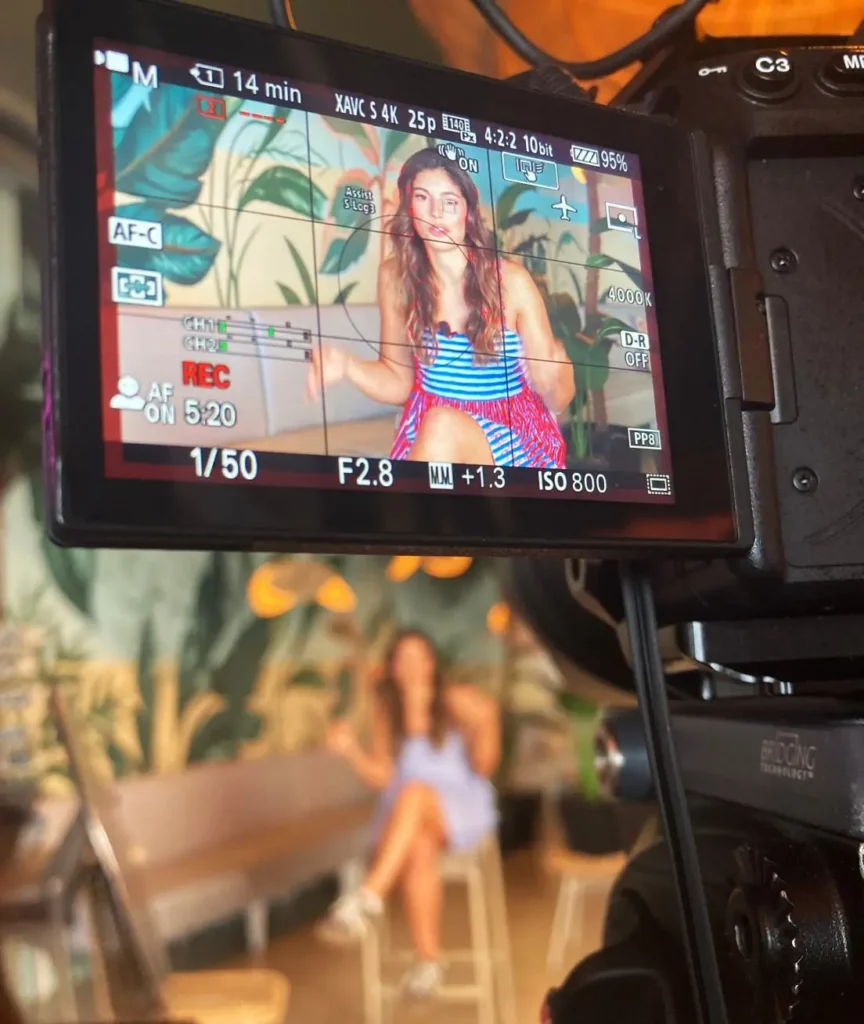 Grabación de entrevista en Madrid con cámara profesional enfocando a una entrevistada en un set con decoración natural