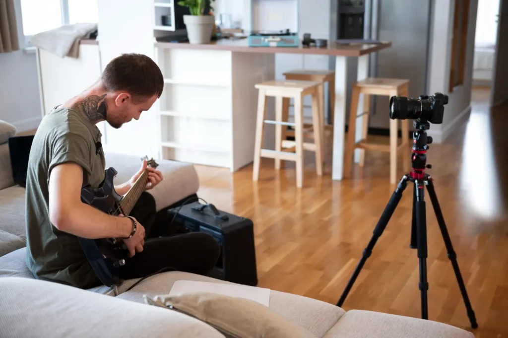 Persona grabando vídeo en casa con móvil sobre trípode y luz natural lateral desde una ventana